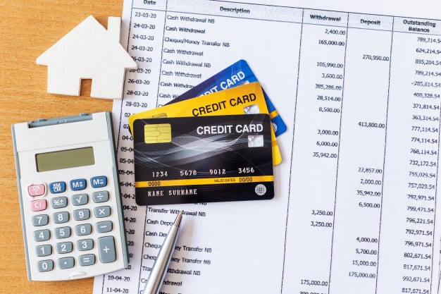 3 credit cards next to a calculator and bank statements