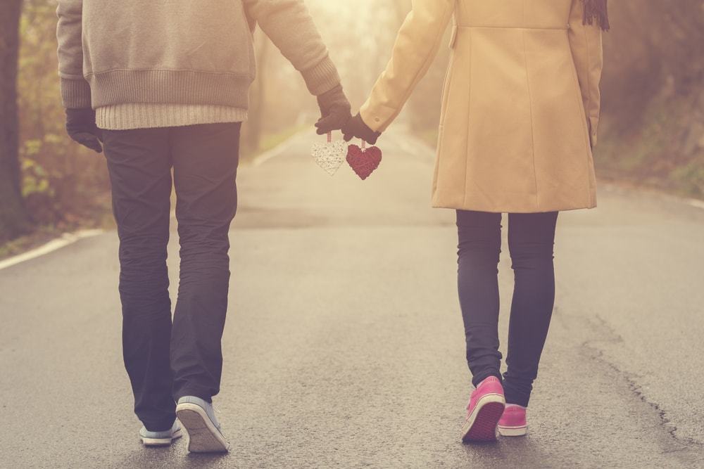 couple holding hands with hearts