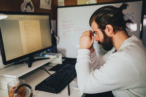 man sitting at his computer looking stressed from work
