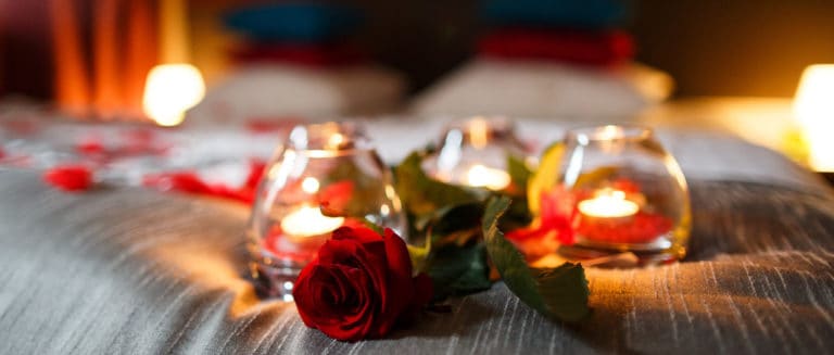 romantic atmosphere - Candles in glass jars and rose petals laid out beautifully on bed