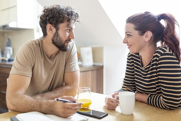 couple having a light but meaningful conversation in the kitchen, looking cheerful