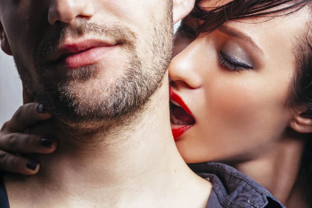 woman kissing a man on the neck