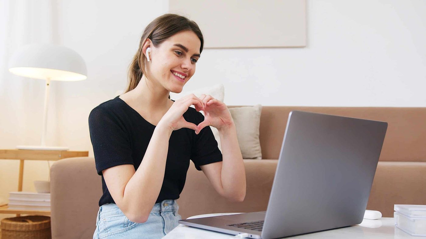 woman on video call with her boyfriend making a heart shape with her hands