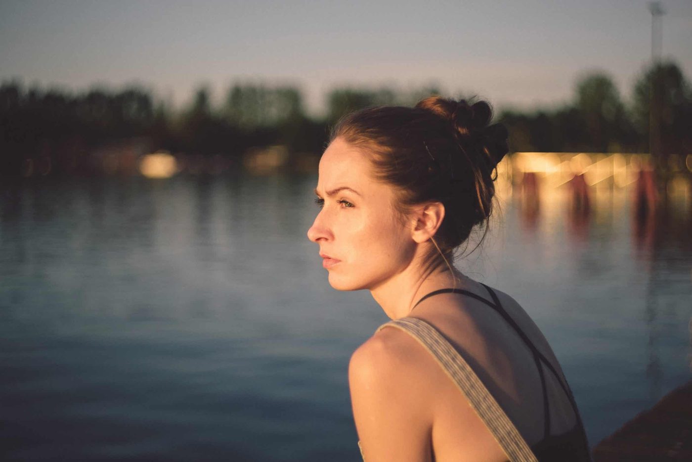 woman standing at the pier at sundown with water in the background