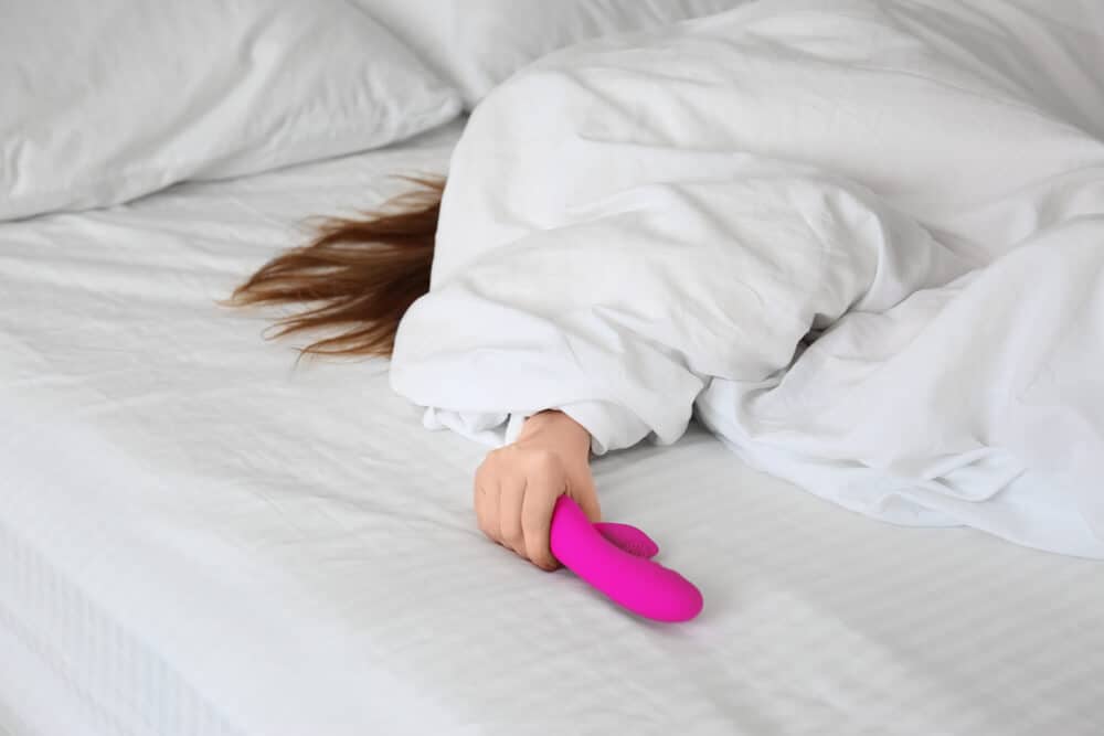 woman holding a vibrator in bed