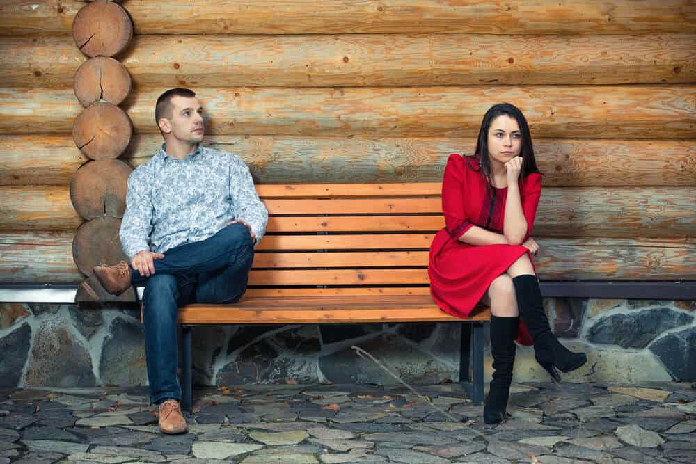 awkward couple sitting on a bench