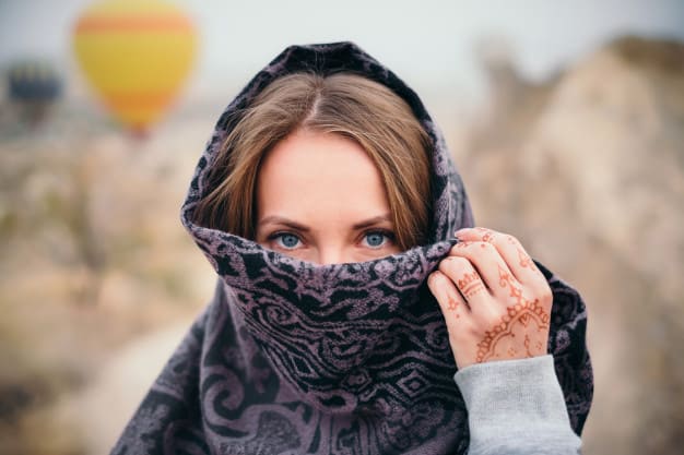 A woman looking at the camera with a scarf covering her face