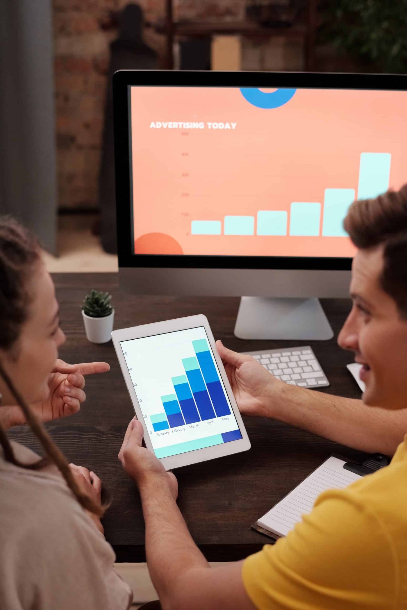 man and woman working closely together looking at a graph in on a tablet