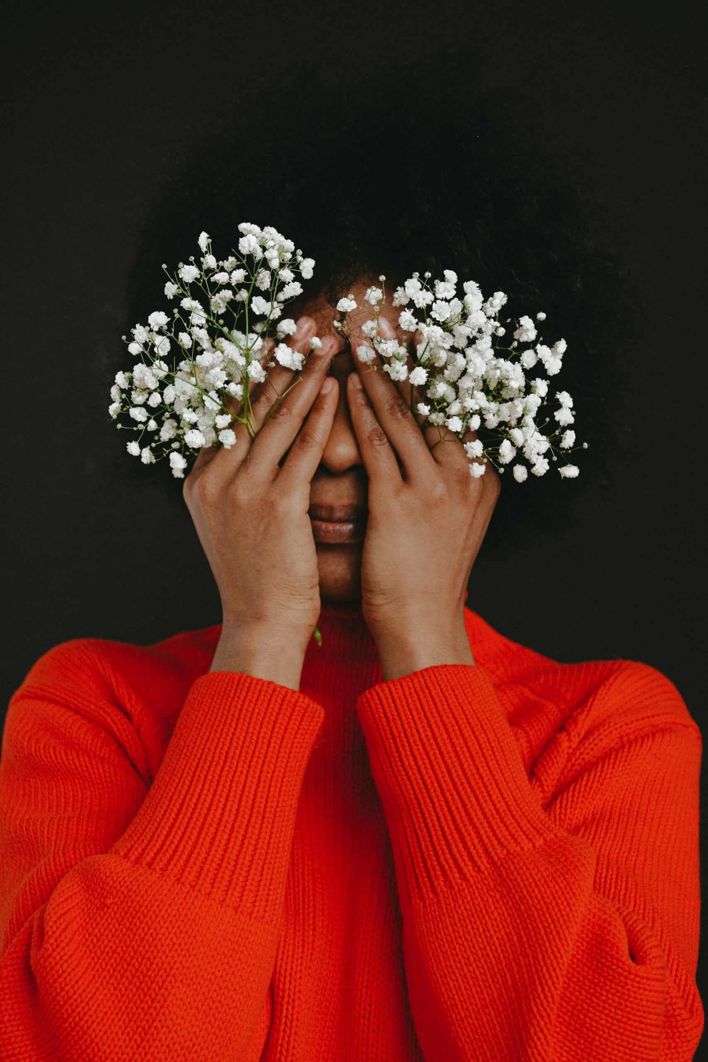 woman holding white flowers covering her face with her hands