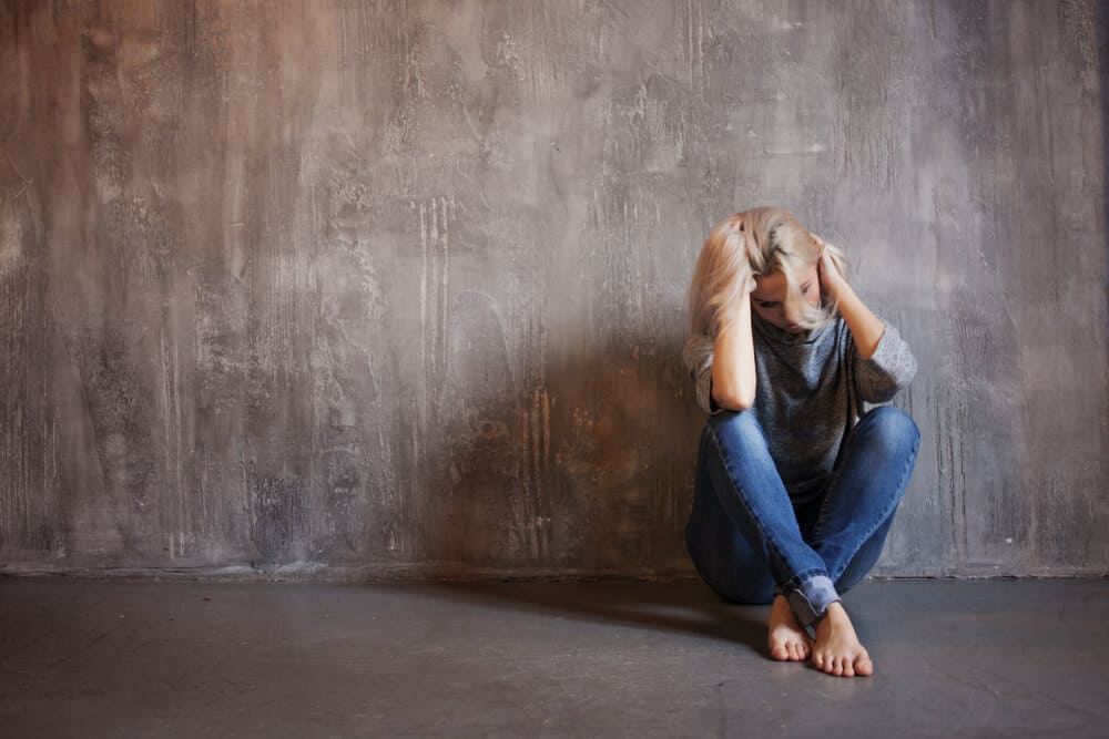 woman sitting alone holding head