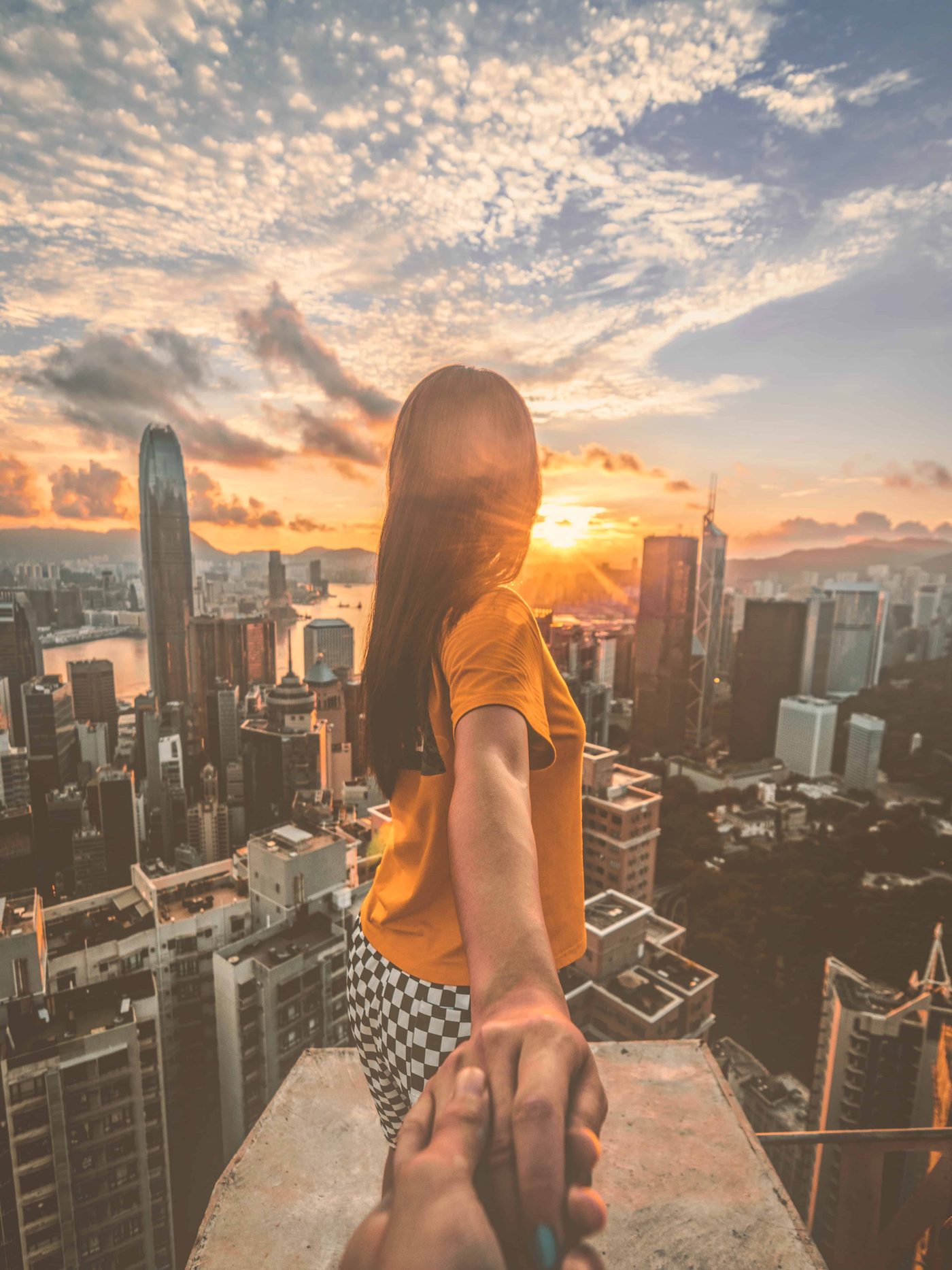 Couple holding hands on a city high-rise, looking out at the skyline