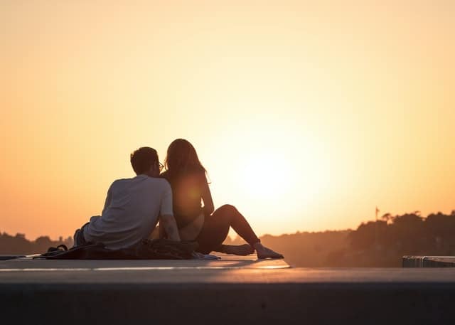 couple sitting together holding each other and talking during sunset