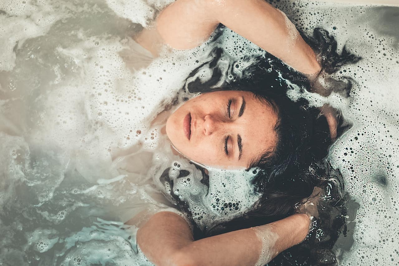 woman taking a bath, washing her hair with her head above the water
