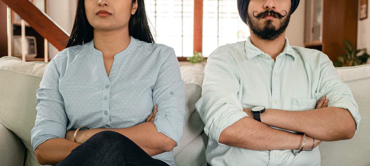 Male and female couple sitting next together and crossing arms in dissatisfaction