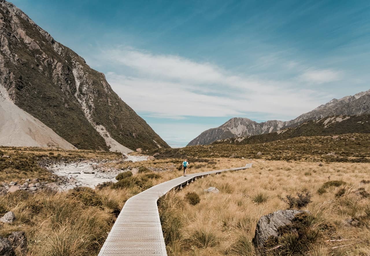 Woman walking down a single beautiful valley trail on mountain landscape