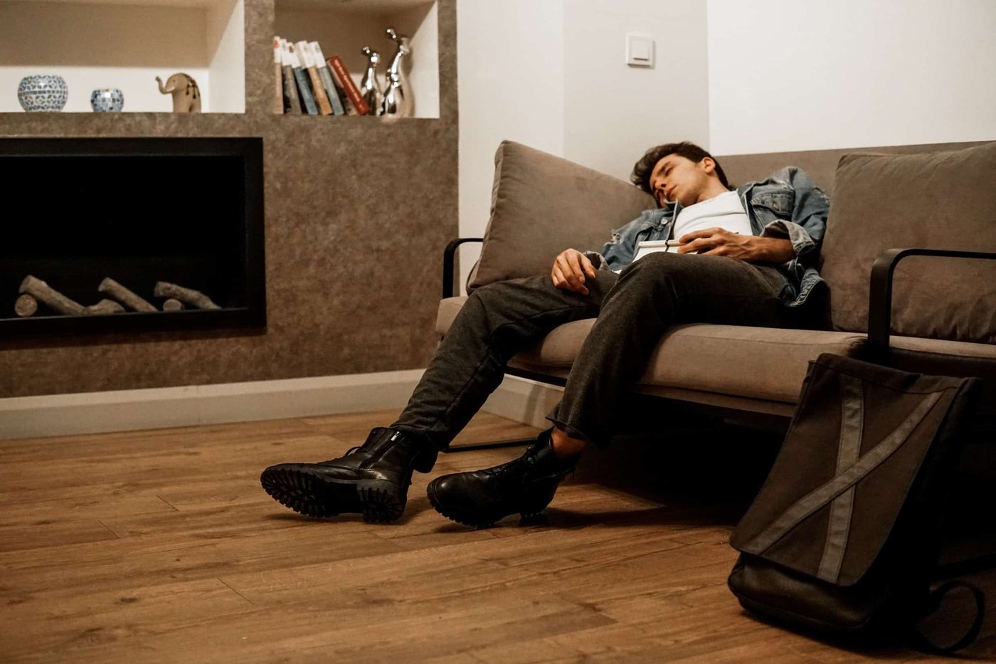 man sleeping on a couch with a blanket covering his body and over his head