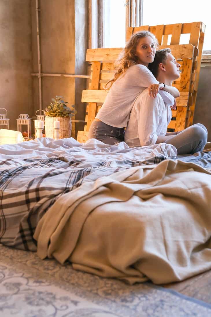 woman hugging man from back on their bed