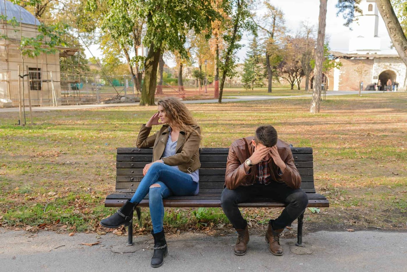 couple sitting on a bench facing away from each other looking upset