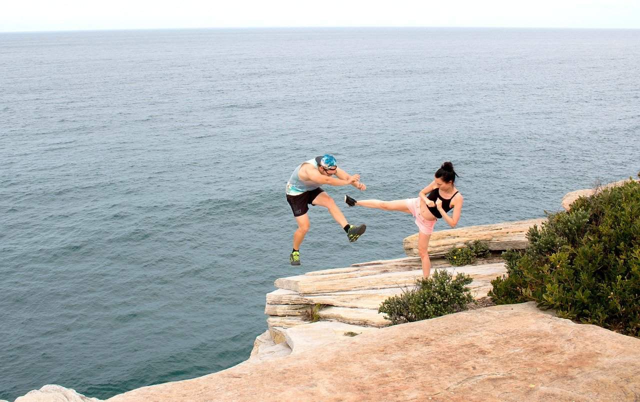 woman "karate kicking" a guy off a cliff