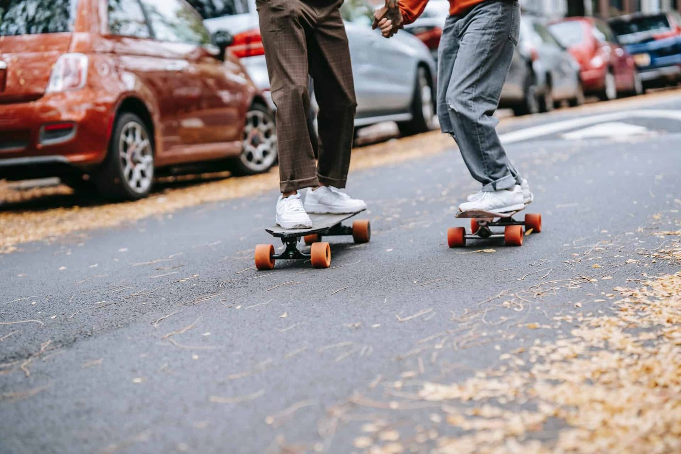 man and woman skateboarding and holding hands