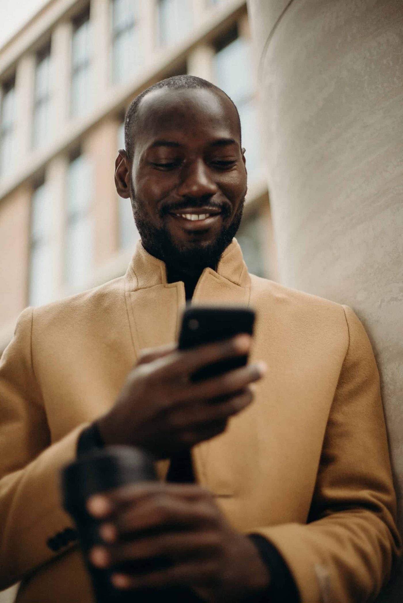 man looking at his phone smiling and reading a text message