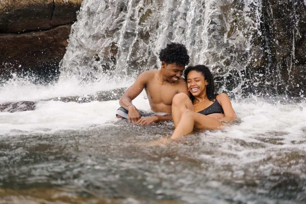 couple sitting under a waterfall laughing