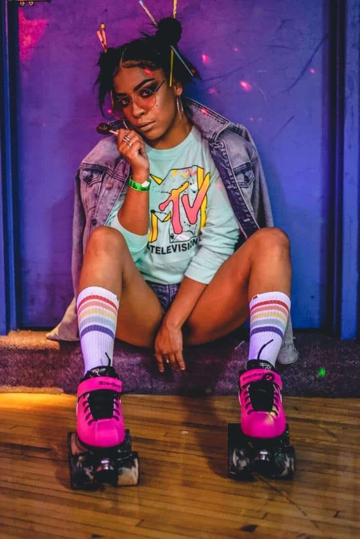 woman in roller skate and bold party clothing sitting on a bench