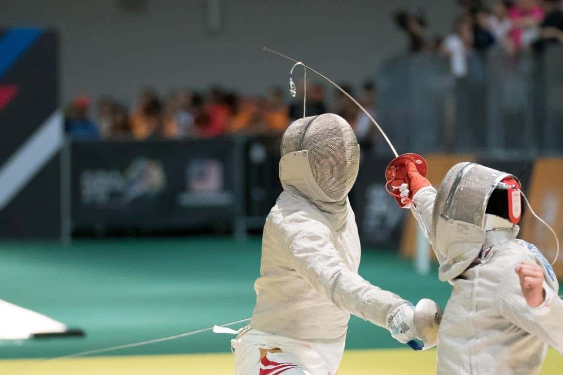 two people fencing during contest, crossing swords
