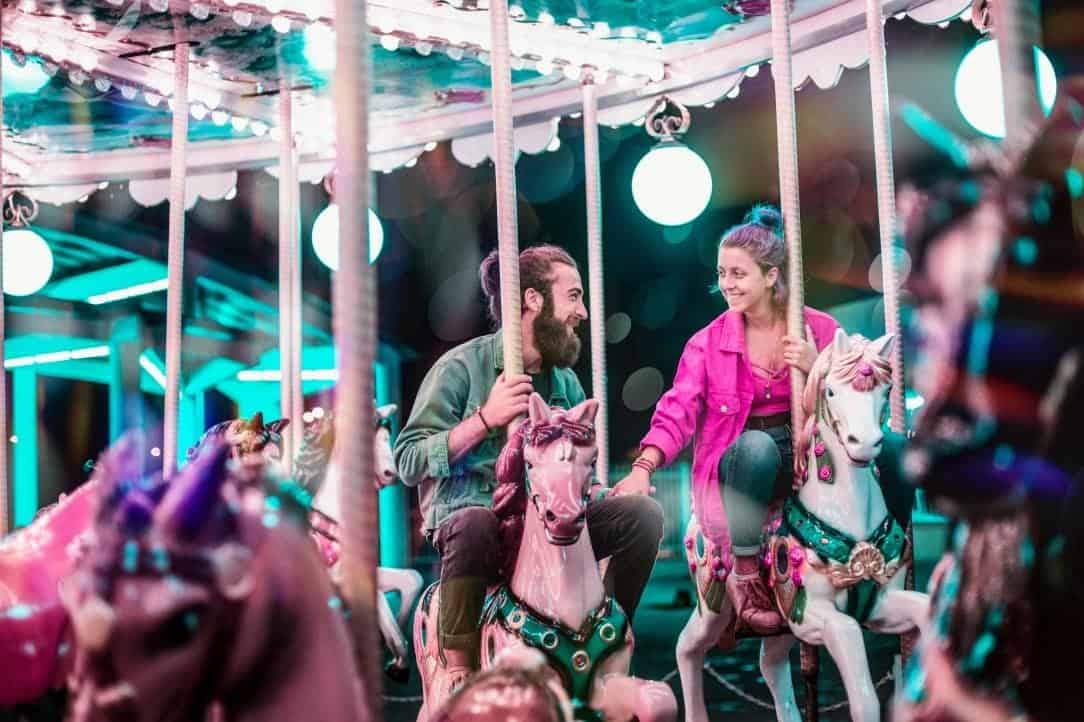 couple smiling on a horse marry-go-round at a carnaval
