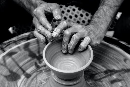 person making clay pottery on pottery wheel