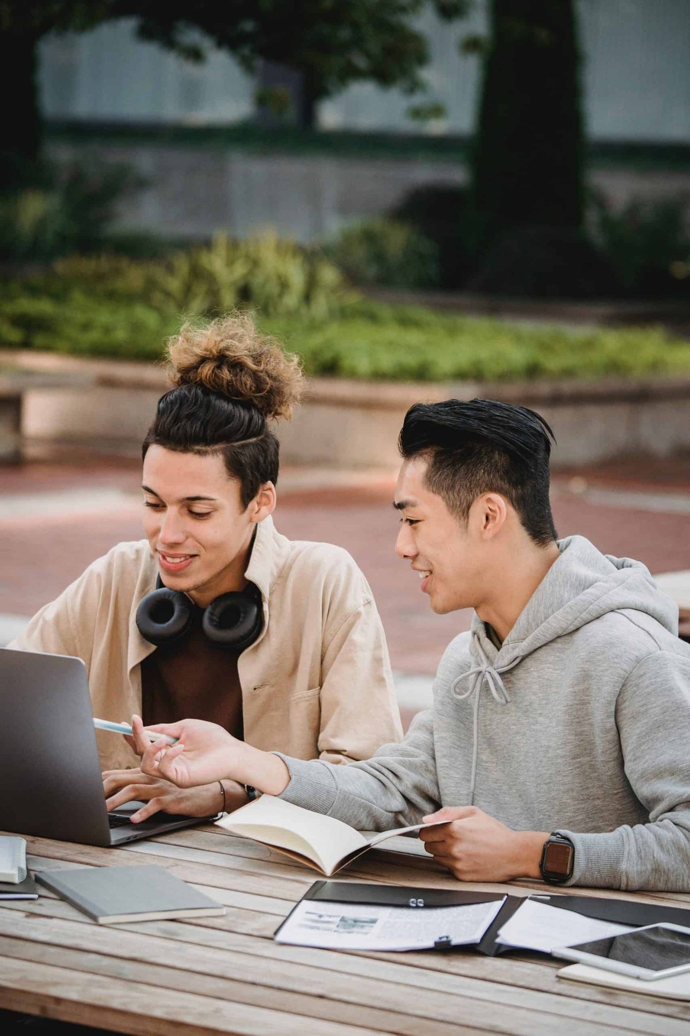 co workers sitting next to each other next to books discussing things on laptop
