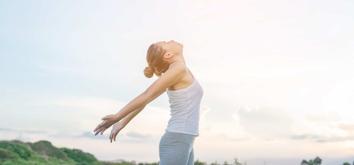 Young woman raising hands with beautiful view