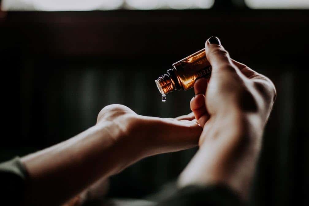 a person dripping massage oil on their palms
