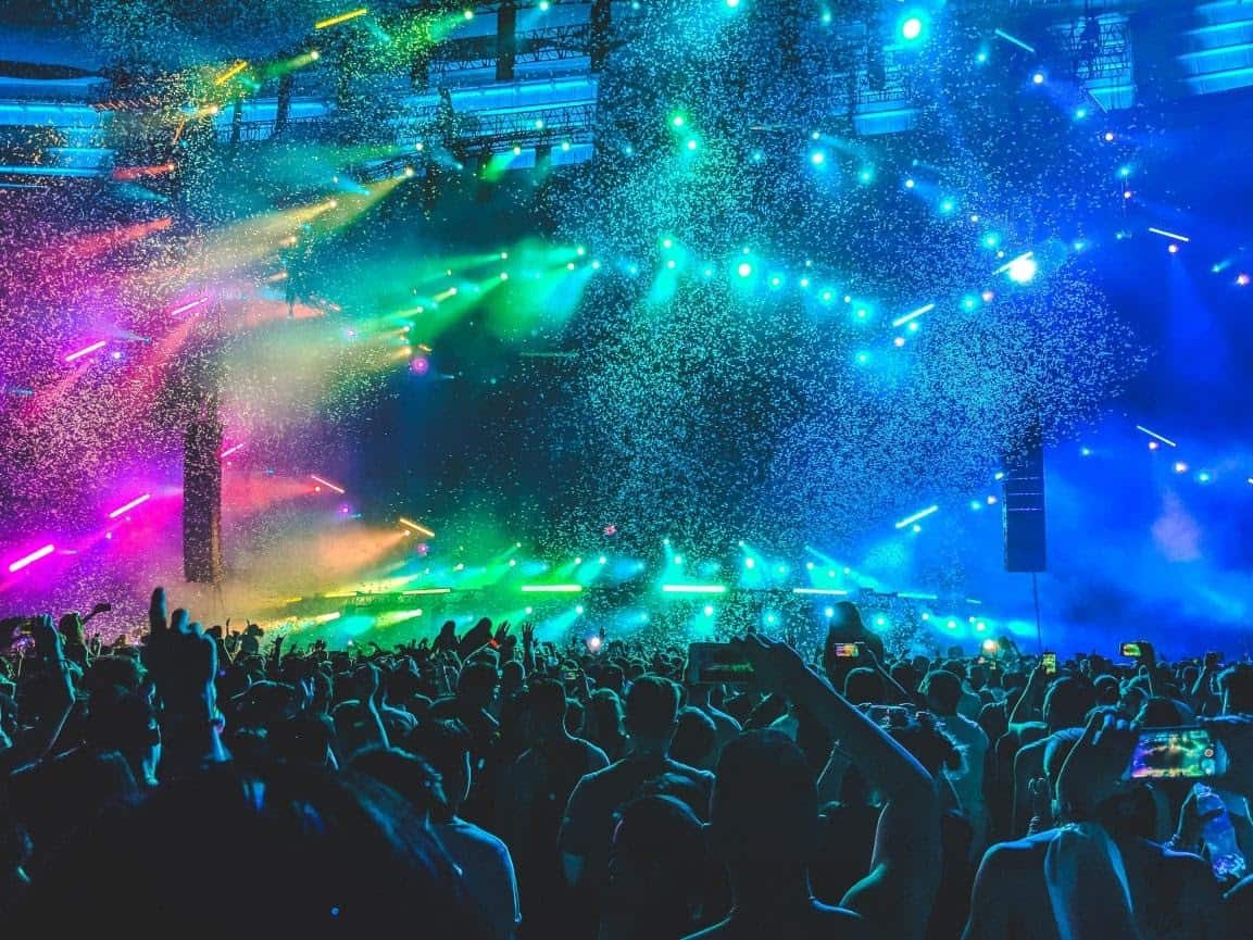 music festival stage with shiny lights, confetti and a dancing crowd