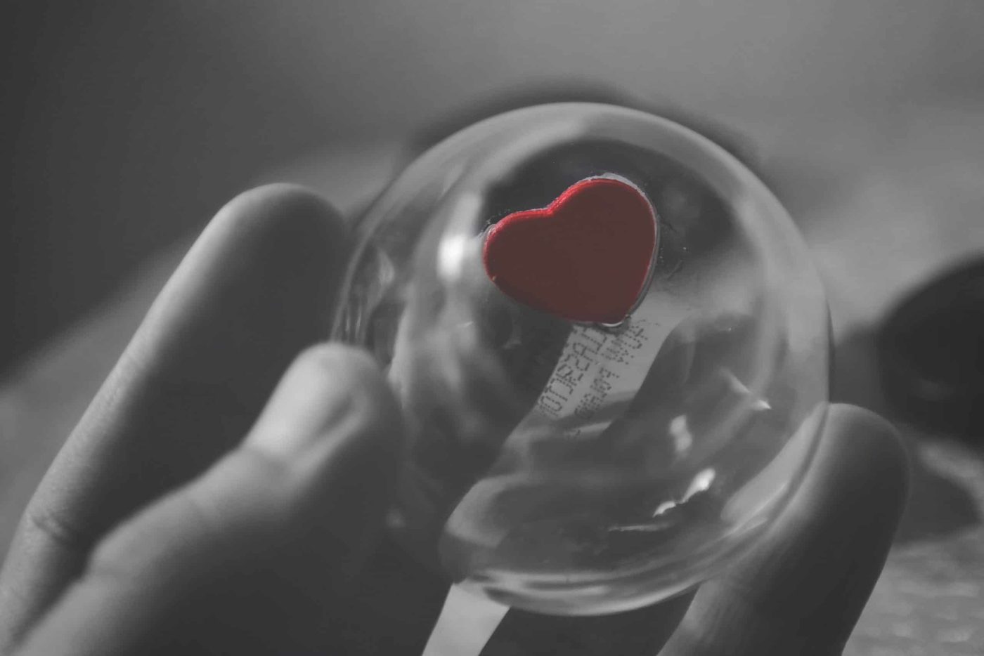 hand holding clear plastic ball with heart on it