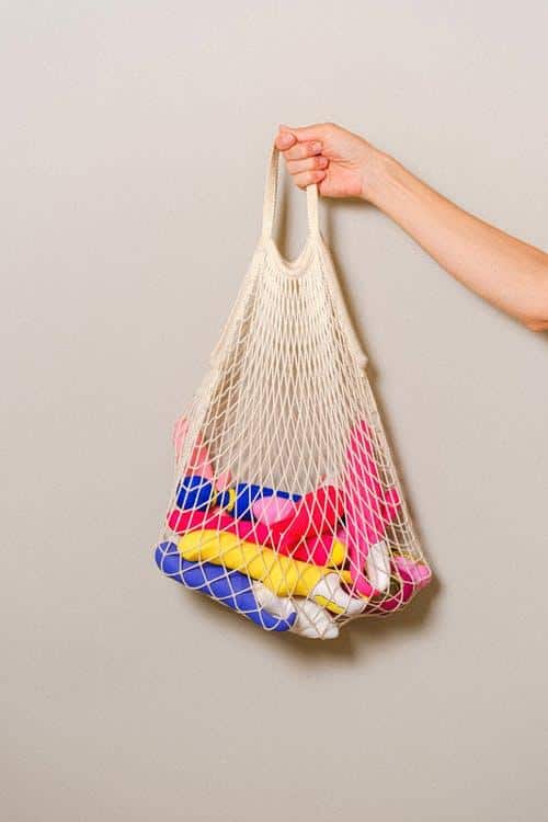 a hand holding a mesh bag with assorted dildos and vibrators