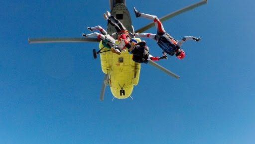 group of people skydiving out of a helicopter