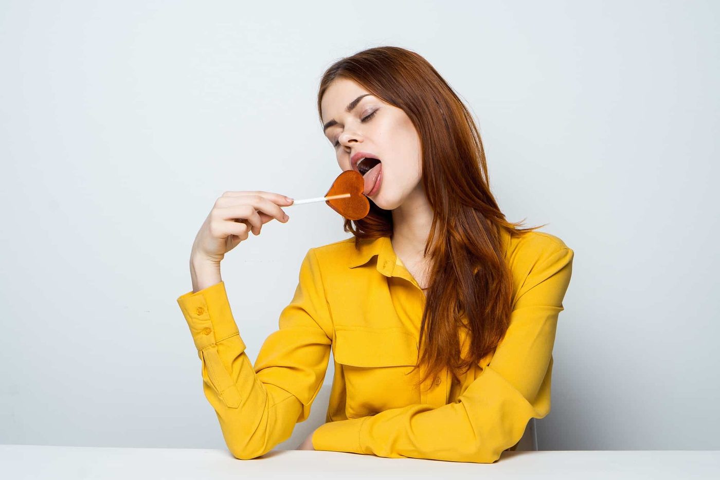 Woman lick lollipop in yellow sweatshirt