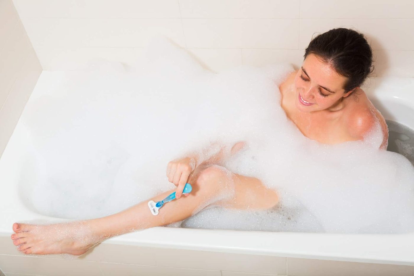 Woman shave legs in foam bath